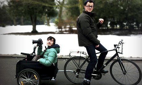 man on a bike with camera man in trailer